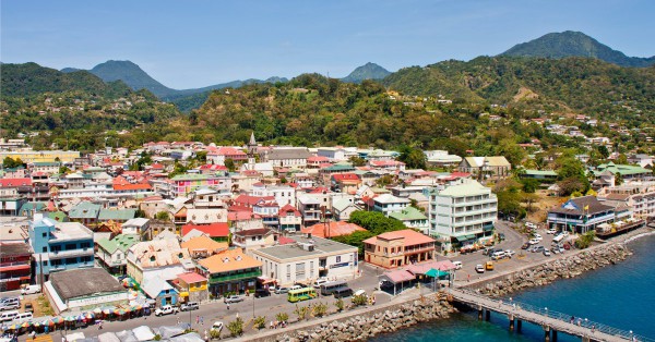 An aerial view of houses, apartments, and buildings. There are also trees and mountains in the distance.